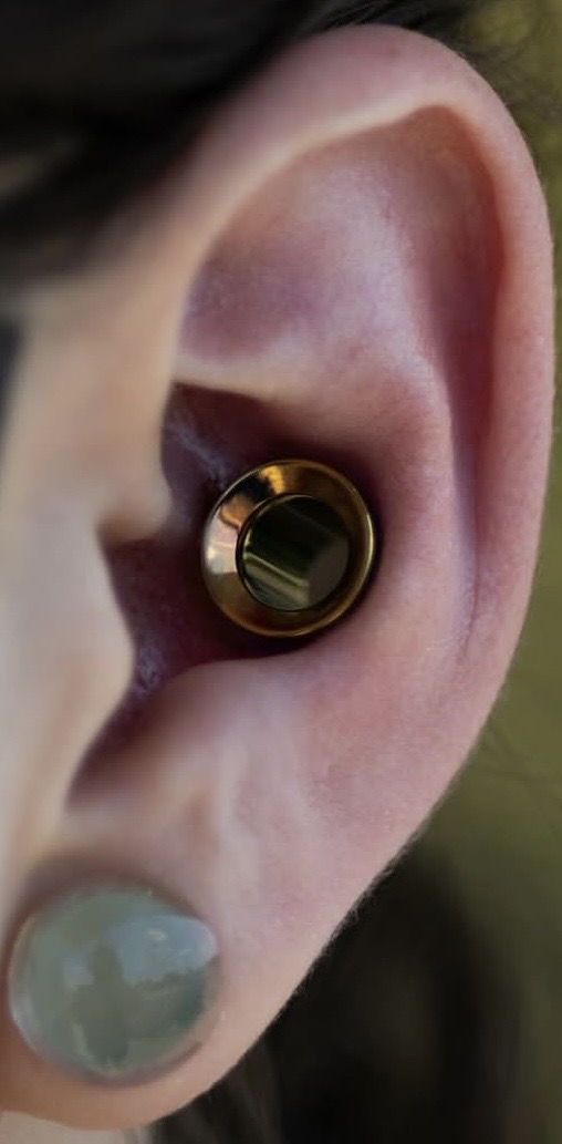 Oreille stylisée avec plusieurs piercings noirs